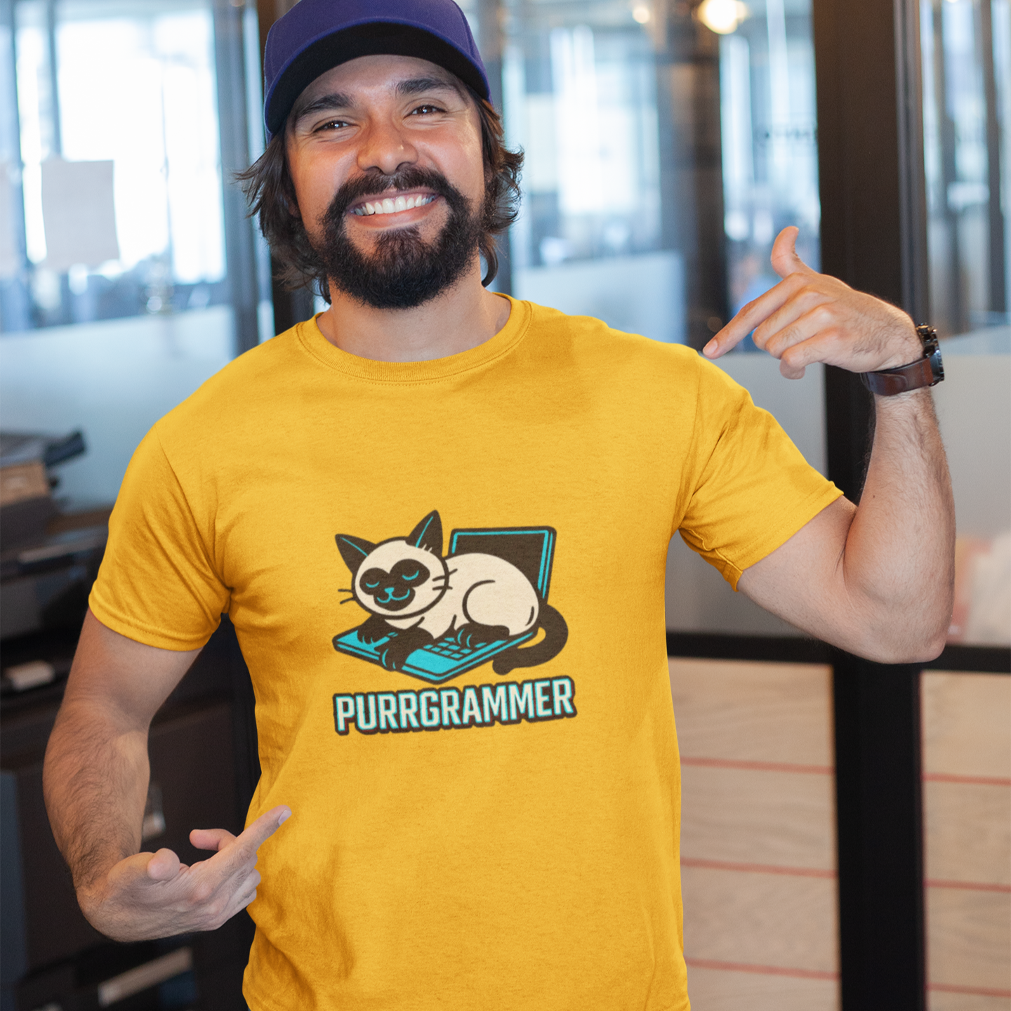 Man wearing a yellow t-shirt with a cat graphic and text, posing indoors.