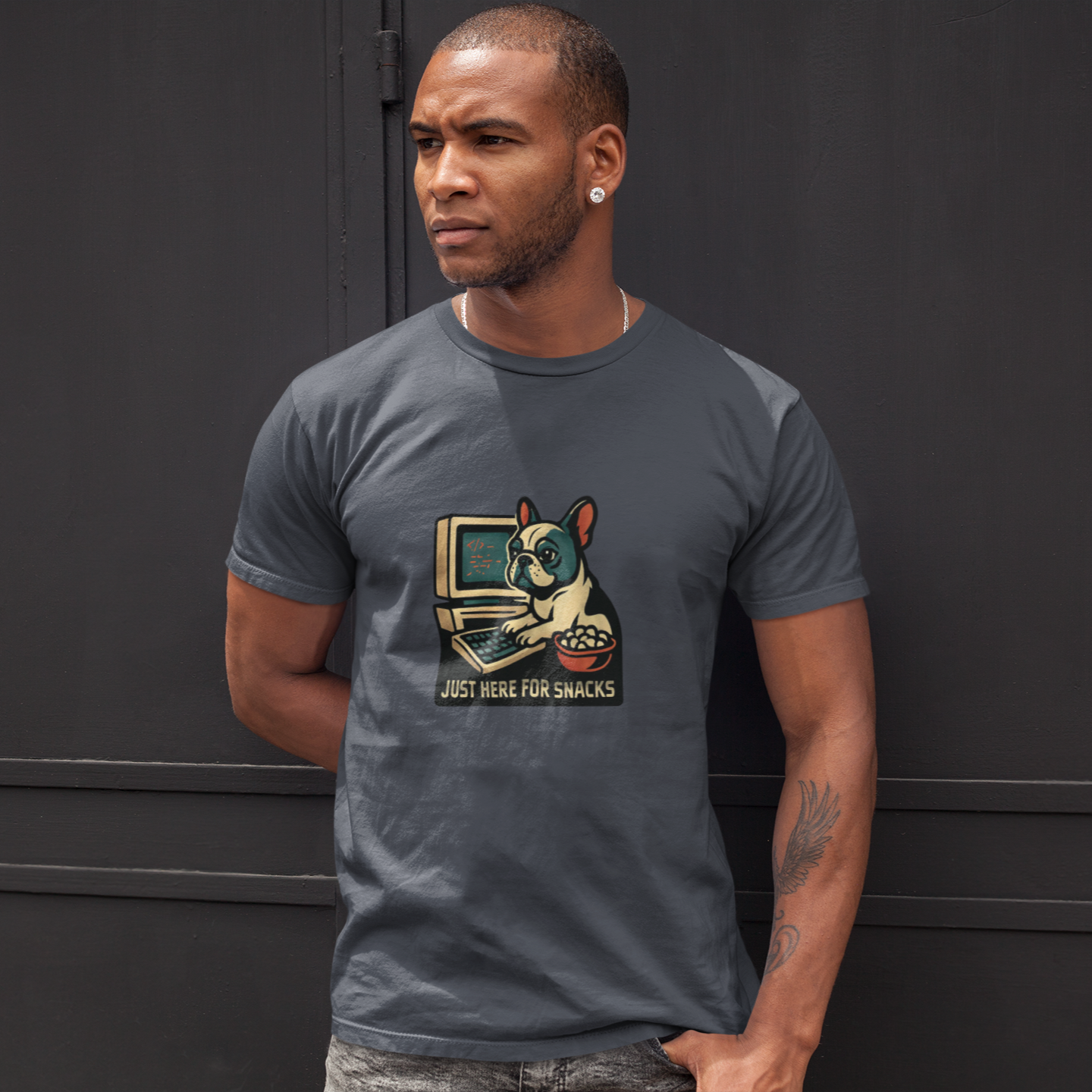 Man wearing a gray t-shirt with a graphic design of a dog and text, standing against a black background.
