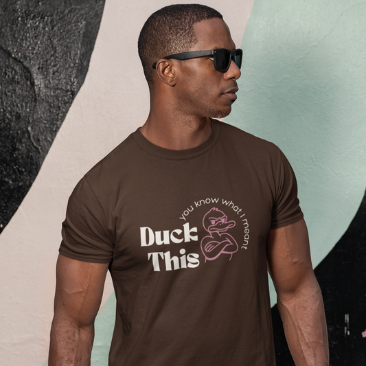 Man wearing a brown t-shirt with 'Duck This' graphic and text, standing against a colorful abstract background.