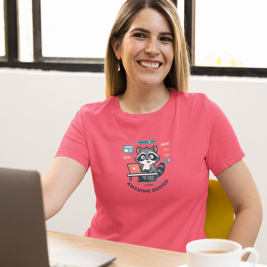 Woman in a pink t-shirt with a raccoon graphic sitting at a desk with a laptop and coffee.