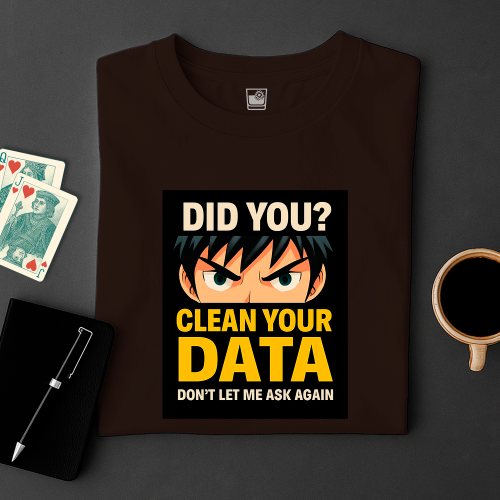 Brown t-shirt with graphic design and text on a dark surface with cards and a cup.
