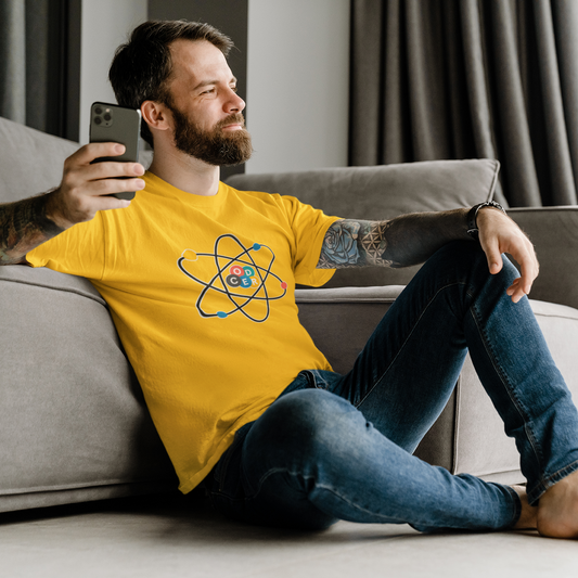 Man sitting on a couch wearing a yellow t-shirt with a logo, holding a phone.