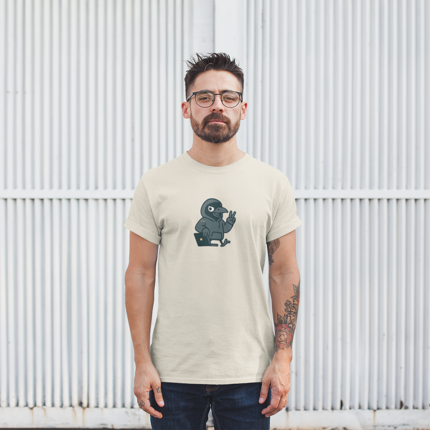 Man wearing a beige t-shirt with a graphic design in front of a white metal fence.