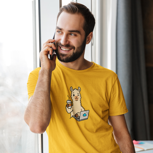 Man wearing a yellow t-shirt with a cartoon llama design, talking on a phone indoors.