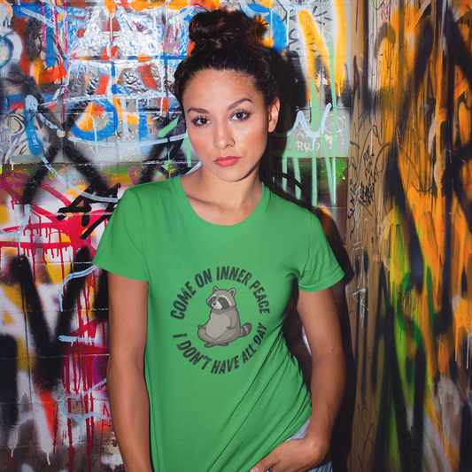 Woman wearing a green t-shirt with text and graphics in front of a graffiti-covered wall.