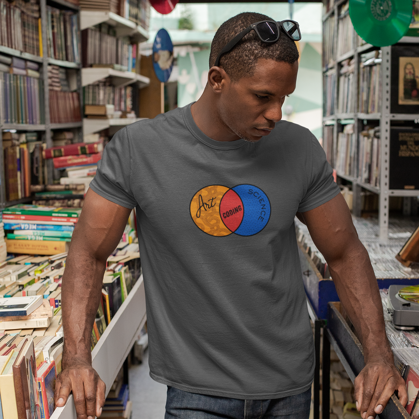 Man wearing a gray t-shirt with a colorful logo in a bookstore