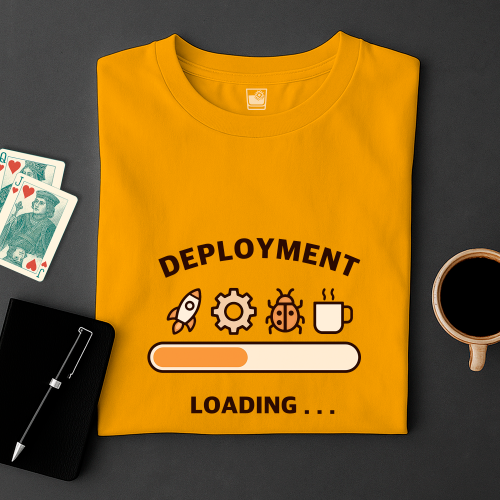 Yellow t-shirt with 'DEPLOYMENT LOADING...' graphic on a dark surface with cards and a cup.