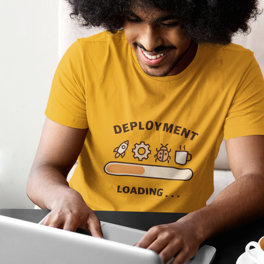 Person wearing a yellow t-shirt with 'Deployment Loading' graphic using a laptop.