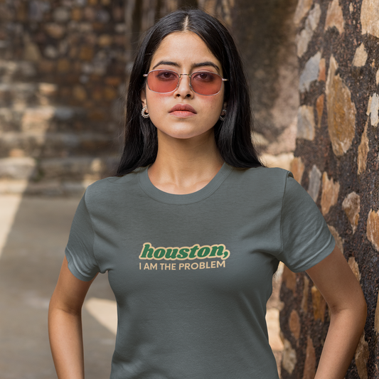 Woman wearing a gray t-shirt with 'houston, I AM THE PROBLEM' text in an outdoor setting.