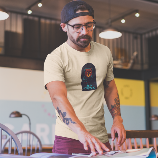 Man wearing a beige t-shirt with a graphic design, standing in an indoor setting.