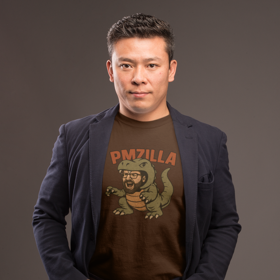 Man wearing a dark blazer over a graphic t-shirt with a logo on a gray background