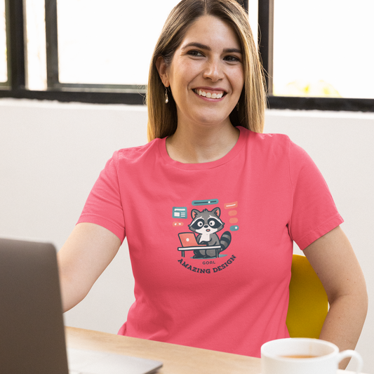 Woman in a pink t-shirt with a raccoon graphic sitting at a desk with a laptop and coffee.