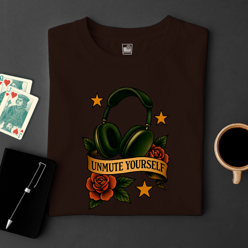 Dark brown t-shirt with headphone design and 'Unmute Yourself' text on a dark surface with cards and a cup.