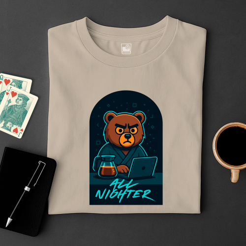 Folded t-shirt with a bear graphic and 'All Nighter' text on a dark surface with cards and a cup.