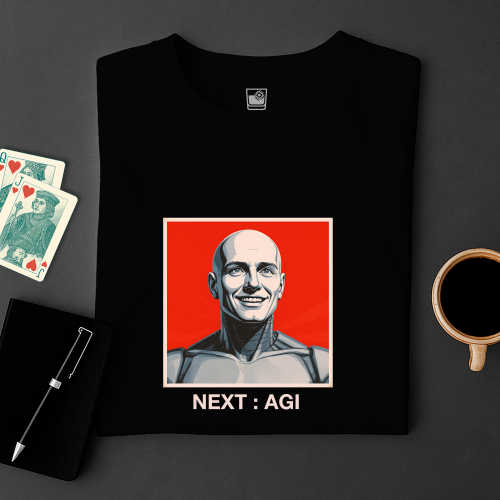 Black t-shirt with a graphic design of a bald man on a red background, text 'NEXT: AGI', placed on a dark surface with playing cards and a coffee cup.