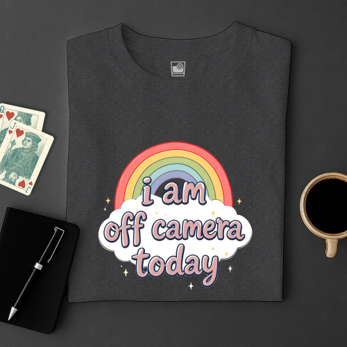 Black t-shirt with rainbow and text design on a dark surface with cards and a cup.