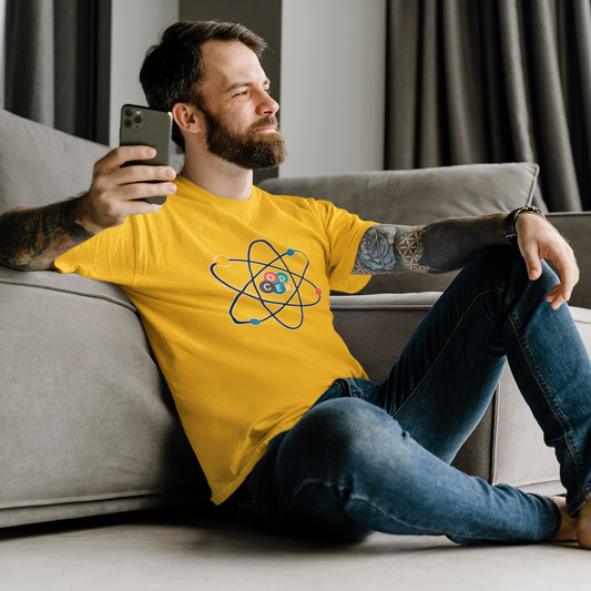 Man wearing a yellow t-shirt with a logo, sitting on a couch and using a phone.