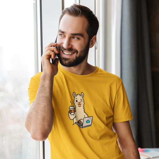 Man wearing a yellow t-shirt with a cartoon llama design, talking on a phone indoors.