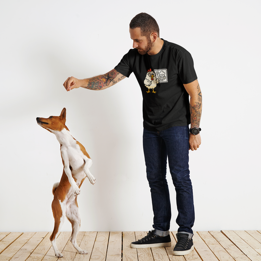 Man in black t-shirt with a graphic design interacting with a dog on a wooden floor.