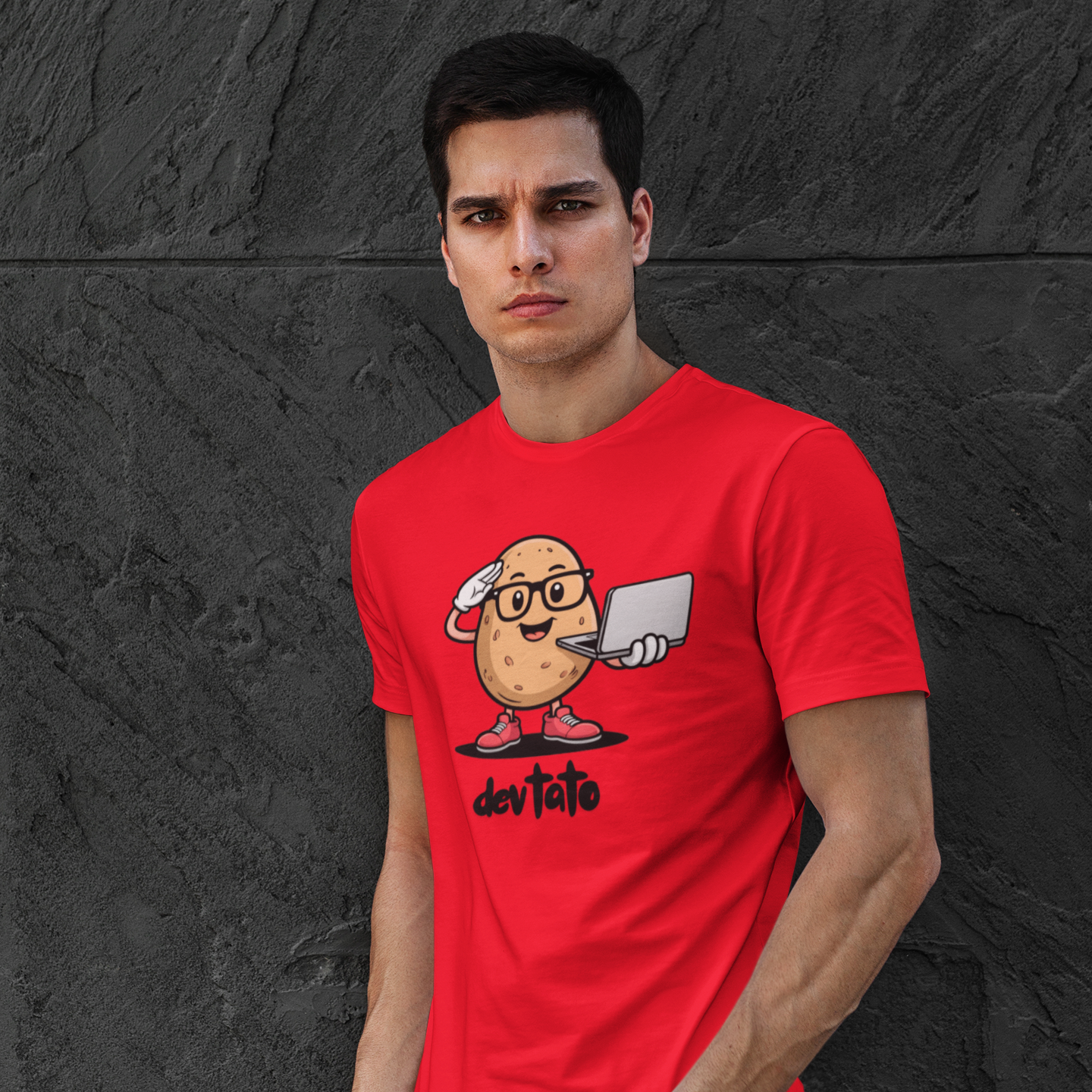 Man wearing a red t-shirt with a graphic design against a black stone wall.