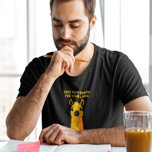 Man wearing a black t-shirt with a llama graphic and text, sitting at a table with a glass of coffee.