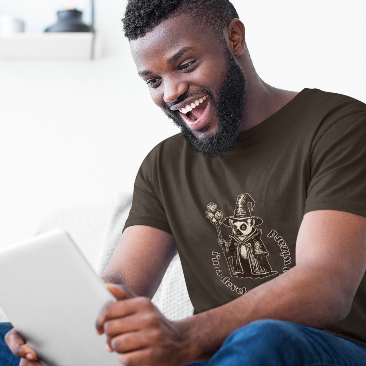 Man sitting on a couch using a tablet with a casual smile.